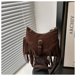 Close-up of brown suede fringe shoulder bag with bohemian metallic buckle and long tassels