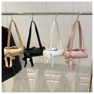 Row of colorful cylinder bags in beige, black, white, and pink with bow charms