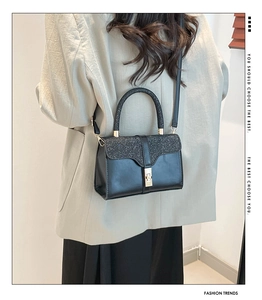 Detail of elegant black sequined crossbody bag with gold metal buckle and handle