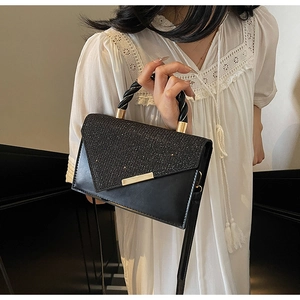 Détail d'un sac à main noir en cuir avec fermoir doré et poignée tressée élégante