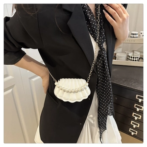 White shell-shaped mini bag with vertical pleats and elegant faux pearl handle on a model