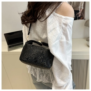 Model wearing black snakeskin textured shoulder bag with elegant gold metal hardware buckles