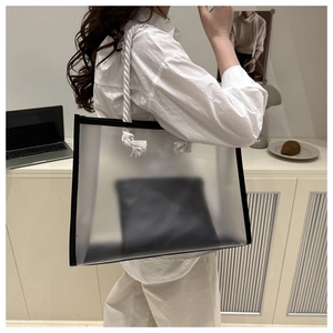 Detail of transparent PVC tote bag with white rope handles and black leather trim