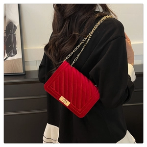 Detail of red velvet shoulder bag with V-shaped quilting and gold chain strap lock