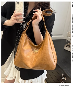 Detail of soft brown tote bag with oval metal FASHION BAGS logo and smooth PU leather