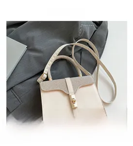 Detail of cream handbag with textured glitter flap and gold rotating metal lock