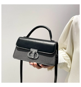 Detail of grey textured fabric crossbody bag with black leather flap and silver clasp
