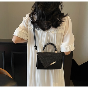 Détail d'un sac à main noir élégant avec poignée torsadée et panneaux de cuir pailleté
