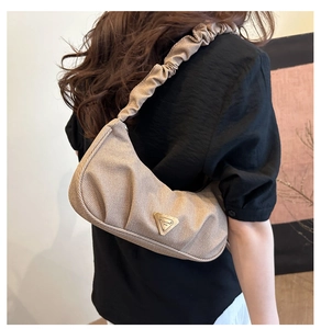 Close-up of beige ruched shoulder bag showing fine fabric texture and golden metal logo