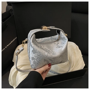Detail of silver snake-pattern handbag with gold hardware on luxury gift box packaging