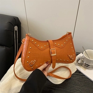 Orange crocodile-patterned shoulder bag with gold studs on a minimalist white backdrop