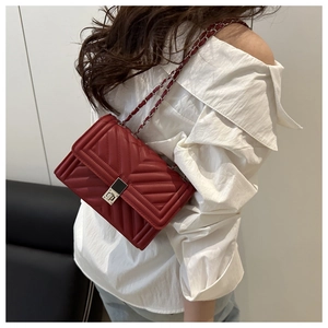 Mannequin portant un sac bandoulière en cuir matelassé bordeaux avec chaîne et fermoir