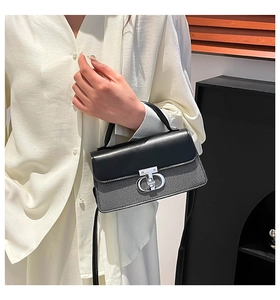 Detail of black and white striped crossbody bag with silver rotating clasp and leather flap