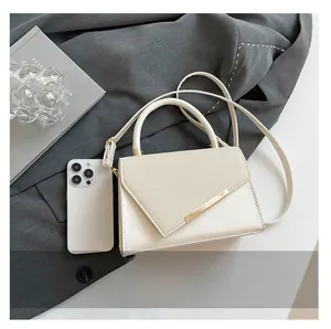 Détail du sac crème avec rabat à texture tissée et bordure métallique dorée