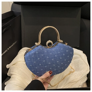 Detailed view of heart-shaped blue denim saddle bag with fringe dots and gold handle