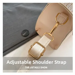 Close-up of adjustable white leather shoulder strap with gold metal hardware on handbag