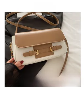 Detail of contrast flap crossbody bag in cream and brown with gold buckles