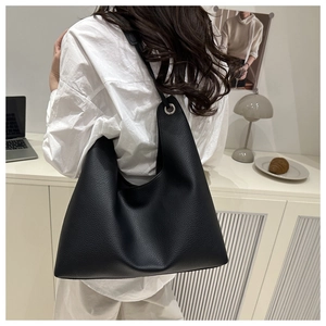 Close-up of black lychee grain leather shoulder bag with large silver metal eyelet hardware