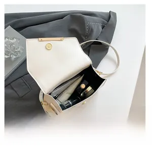 Intérieur spacieux du sac à bandoulière blanc montrant téléphone et cosmétiques