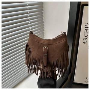 Detail of brown suede tassel shoulder bag with golden buckle in natural sunlight