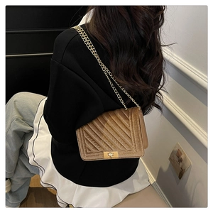 Detail of camel velvet crossbody bag with elegant quilted pattern and golden metal lock