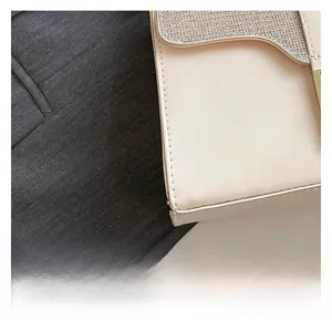 Detail of a beige leather crossbody bag featuring a silver sequined flap and gold hardware