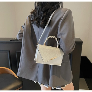 Petit sac carré argenté avec patchwork pailleté et poignée spirale sur un mannequin