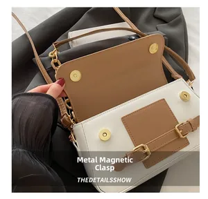 Detail of color-block leather crossbody bag showing magnetic snap closure and gold hardware