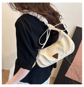 Detail of beige pleated cloud bag with scrunchie strap and bow on female model