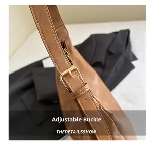 Close-up of adjustable gold buckle and white stitching on brown leather shoulder bag strap