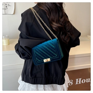 Detail of dark green velvet shoulder bag with quilted texture and gold chain strap