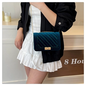 Detail of dark green velvet shoulder bag with quilted texture and golden twist lock