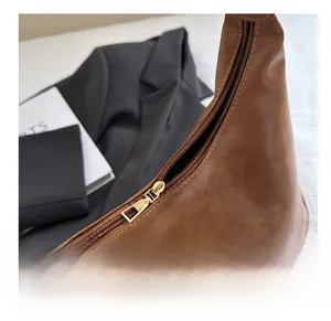 Close-up of smooth gold metal zipper and vintage brown leather texture on backpack