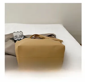 Close-up of the durable reinforced stitching on the flat base of the tan faux leather tote bag