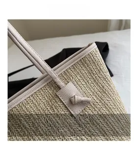 Close-up of woven straw tote bag featuring v-pattern texture and knotted leather trim