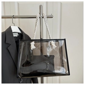 Detail of transparent PVC tote bag featuring rope handles and black interior pouch