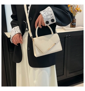 Détail d'un sac à main blanc en cuir avec rabat tressé et garniture dorée élégante