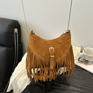 Retro brown suede fringe crossbody bag with metallic buckle in a warm lifestyle setting