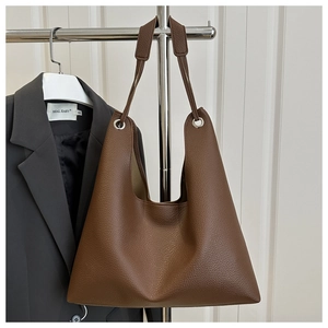 Detail of deep brown pebble grain leather texture on a minimalist large hobo tote bag
