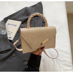 Détail du sac beige élégant avec rabat doré scintillant et poignée tressée chic