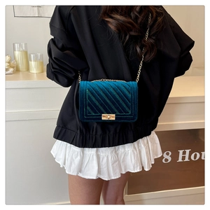 Detail of green velvet crossbody bag showing quilted texture and gold metal chain strap