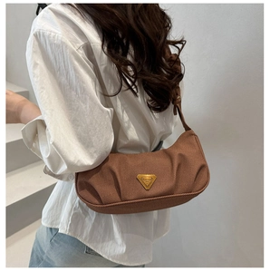 Detail of a brown pleated canvas shoulder bag with a gold triangular metal logo for women