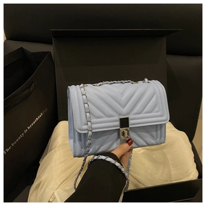 Détail du sac à chaîne matelassé bleu clair avec coutures en V et fermoir rotatif en métal