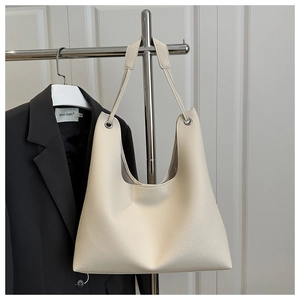 Close-up of beige lychee leather tote bag with silver metal ring on office apparel background
