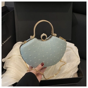 Detail of light blue textured evening bag with golden metal handle in a gift box