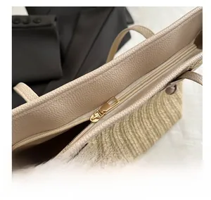 Detail of golden metal zipper and pebble grain leather trim on straw tote bag
