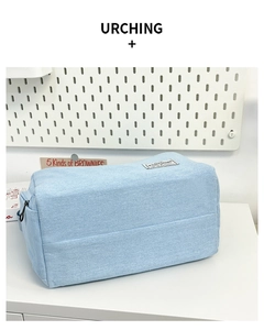 Détail de la trousse de maquillage en jean bleu clair avec fermeture éclair noire et étiquette