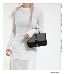 Detail of minimalist black handbag with silver artistic metal handle and buckle