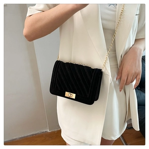 Quilted velvet shoulder bag with gold twist lock worn by a model in a beige suit
