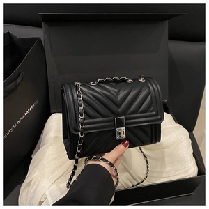 Détail du sac bandoulière noir matelassé avec surpiqûres en V et fermoir argenté